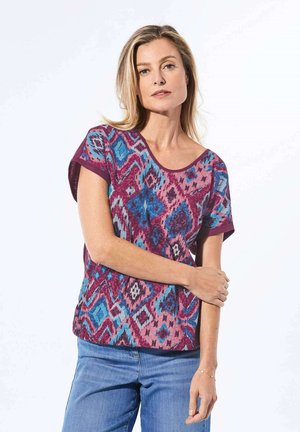 T-shirt à manches courtes avec un col rond, présentant un motif géométrique multicolore dans des tons de bleu et de violet. Tissu doux, coupe décontractée.