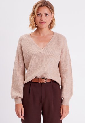 Maglione beige a maglia con scollatura a V, texture a costine e spalle scese, abbinato a pantaloni marroni a vita alta e una cintura marrone.