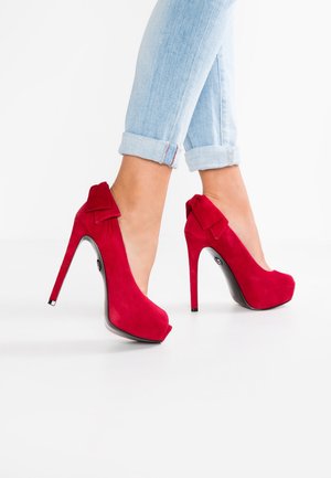 Escarpins rouges en daim avec un design peep-toe et un nœud décoratif à l'arrière ; dotés d'un élégant talon aiguille noir.