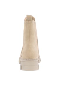 Botín de ante beige con suela de goma gruesa, paneles laterales elásticos y una pequeña lengüeta en la parte trasera. Diseño minimalista con detalles de costura.