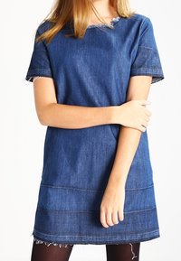 Robe en denim bleu foncé avec des manches courtes, encolure et ourlets effilochés, présentant une coupe droite et des détails de couture horizontale.