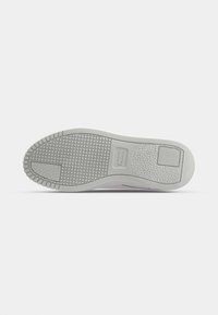 White athletic shoe sole with textured grip pattern and circular details. Features a solid grey midsole with a subtle logo imprint.