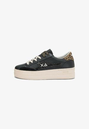 Zwarte sneaker met een platte platformzool, voorzien van een glanzend sterrenlogo, beige veters en een dierenprint accent op de hiel. Gevoerde leren bovenkant.