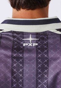 Vue arrière d'une personne portant un maillot de sport à motifs foncés avec un col blanc et un logo "PXP" sous l'encolure.
