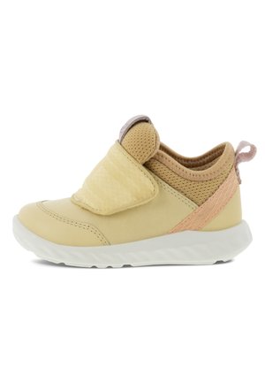 Beige peutersneaker met klittenbandsluiting, ademende mesh enkelondersteuning, roze lus bij de hiel en witte, gestructureerde zool.
