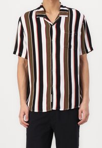 Lyhythihainen nappipaita, jossa on pystysuorat raidat valkoisena, mustana, oliivinvihreänä ja punaisena. Ominaisuuksina rintatasku ja rento malli.