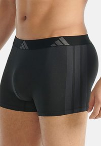 Svarta boxershorts med en slät yta, med en midjeresår som har en subtil tre-randig design och ett prickigt mönster på tyget.