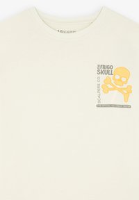 Crème-kleurig katoen t-shirt met een gele doodskop en gekruiste botten graphic en de tekst "THE FRIGO SKULL" en "SCALPERS CO." op de voorkant.