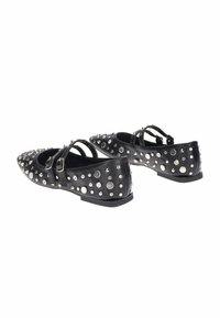 Scarpe basse nere a punta con doppie cinghie, decorate con borchie argentate e strass, presentate su uno sfondo bianco.