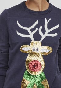 Granatowy sweter z wzorem renifera, udekorowany złotymi i czerwonymi cekinami, białymi rogami oraz dolną częścią w zielonym i brązowym kolorze.