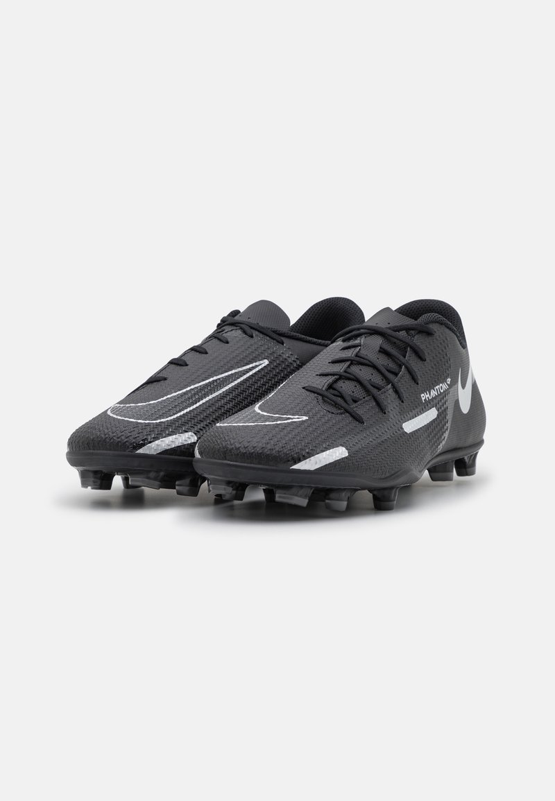 Botas de fútbol negras con parte superior de malla texturizada, que presentan acentos en blanco y un diseño aerodinámico. Tacos en la suela para tracción.