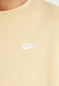 Svijetlosmeđi dukserica s okruglim izrezom, izrađena od pamuka, s malim izvezenim bijelim Nike logotipom na lijevoj strani prsnog područja.