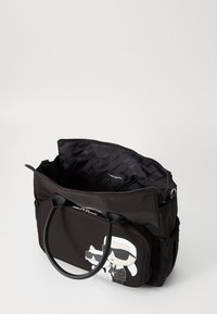 Zwarte nylon draagtas met dubbele handvatten, ritssluiting, binnenvoering en een cartoonafbeelding van een man en kat in zonnebrillen op de voorzak.