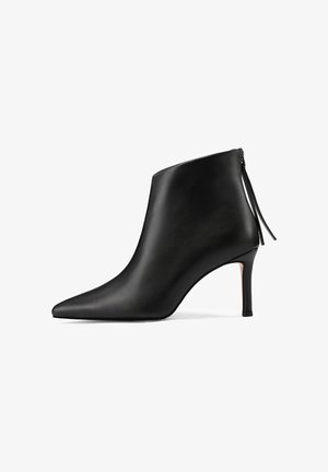 Stivaletto in pelle nera con punta affilata, texture liscia e tacco sottile. Presenta una chiusura con zip e un design affusolato.