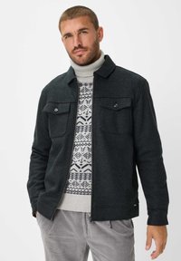 Donkergrijze jas met twee borstzakken, gecombineerd met een dikke, gestreepte crèmekleurige trui met blauwe en grijze ontwerpen. Geweven stof, casual pasvorm.