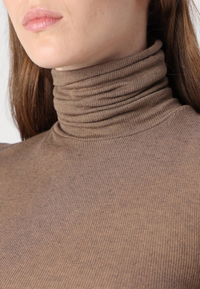 Brauner gerippter Rollkragenpullover mit taillierter Passform. Der Stoff wirkt weich mit einer gemütlichen Textur und hat einen hohen, gefalteten Kragen.