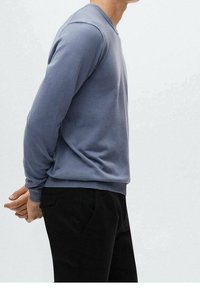 Sweatshirt en coton bleu clair à manches longues et col rond, associé à un pantalon noir. Texture lisse, coupe ajustée.