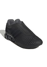 Zapatilla negra Adidas con diseño de malla, cierre de cremallera y elementos de suela únicos en forma de resorte, mostrada sobre un fondo blanco.