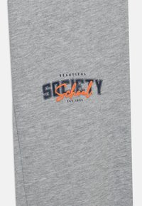 Szary sweatshirt z graficznym napisem w granatowym i pomarańczowym kolorze, z napisem "PIĘKNE SZKOŁY SOCJALNE EST. 1986." Wykonany z miękkiego materiału o gładkiej fakturze.