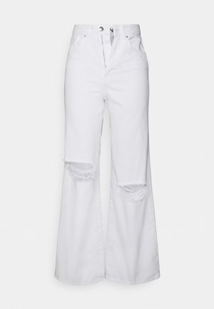 Calças largas brancas em denim, apresentando recortes desgastados nos joelhos e fecho com botões. Textura suave com um corte descontraído.