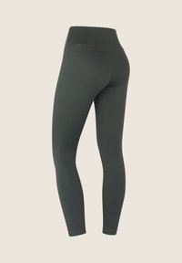 Leggings verdes de talle alto hechos de un material liso y elástico. Diseño ajustado sin patrones visibles ni detalles de herrajes.