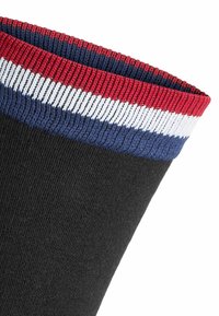 Schwarze Socke mit einem gerippten Bündchen, das rot, weiß und blau gestreift ist. Glatte Textur und tapered Design.