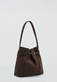 Bolso de ante marrón con un diseño flexible, una sola correa larga y un acento de hebilla metálica cerca de la parte superior. Textura suave, estilo minimalista.