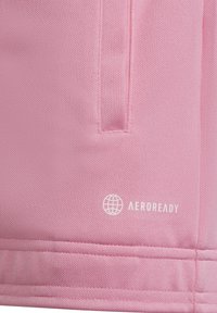 Rosa sportshorts i tyg med texturerad yta, sidofickor och en "AEROREADY"-logga i vitt på nedersta högra sidan.