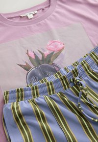 Lilac cotton t-shirt with floral graphic, paired with light blue shorts featuring vertical green and yellow stripes and an elastic waistband.
