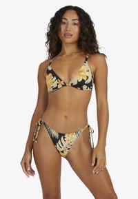 Bloemige bikini set met een zwarte basis en gele en groene tropische patronen, driehoekige top met verstelbare bandjes en bikinibroekje met knoop aan de zijkant.