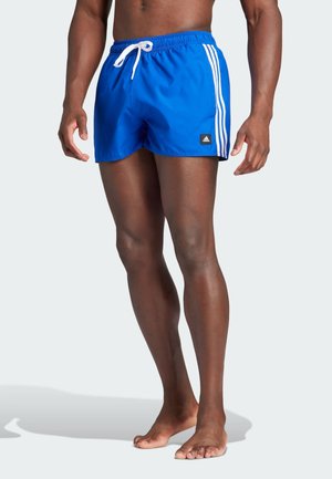 Pantaloni da bagno blu con strisce laterali bianche, realizzati in materiale leggero. Dotati di cintura elastica e di un piccolo patch del logo del marchio nero.