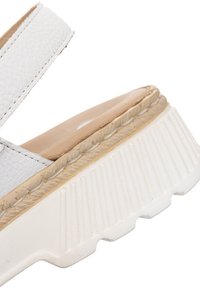 Sandalia de cuero blanca con un upper texturizado, plantilla beige y suela de goma blanca gruesa con surcos pronunciados.