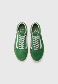 Paire de baskets en daim vert avec des bandes blanches sur les côtés et des lacets blancs, vues de dessus sur un fond blanc uni.