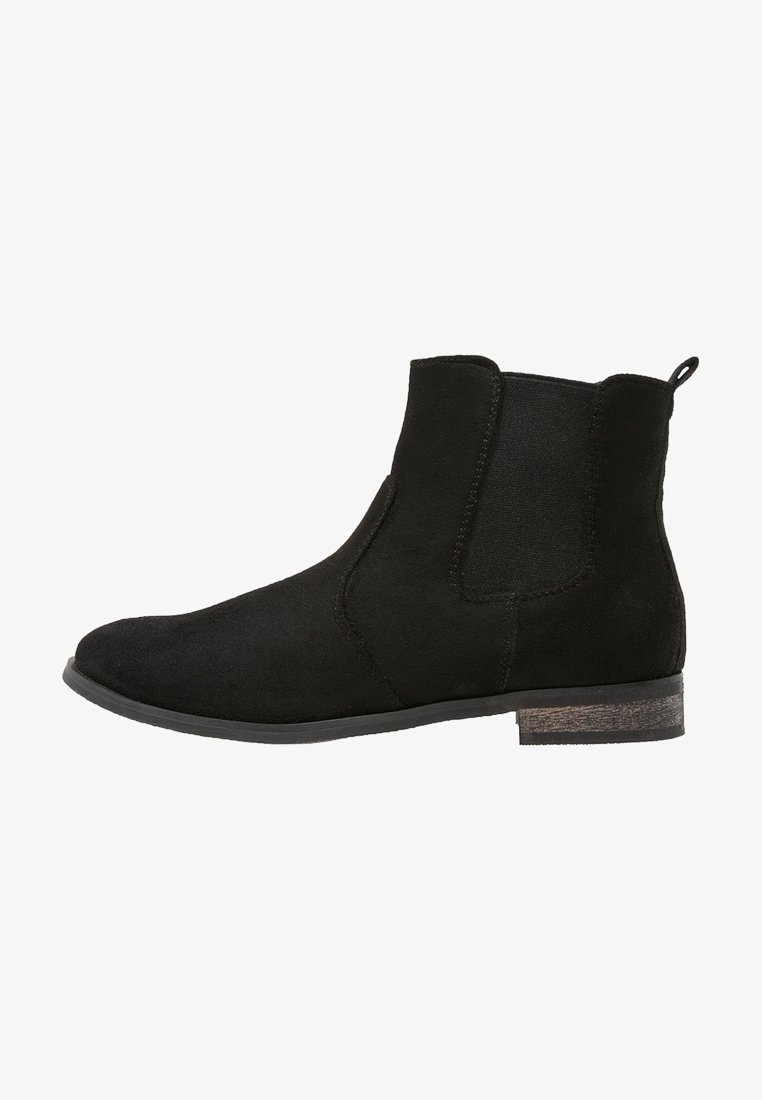 Bottine Chelsea en daim noir avec panneaux latéraux élastiques, languette à l’arrière et petit talon en bois empilé.