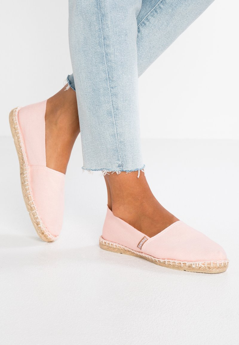 Pink canvas espadrilles with a jute sole, featuring a slip-on design and a low profile. Light texture with contrasting stitching detail.