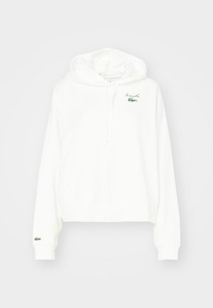 Weißer Hoodie aus weichem Baumwollstoff, mit einer Kängurutasche, einer Kapuze mit Kordelzug und einem kleinen grünen Krokodil-Logo auf der Brust.