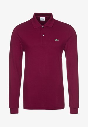 Polo de manga larga color burdeos, hecho de algodón texturizado, con cuello clásico y dos botones, con un pequeño logo verde de Lacoste en el pecho.