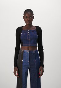 Farmer minta cropped top kék anyagból, gombokkal, magas derekú, két színű farmernadrággal párosítva, amely sötét és világoskék panelekből áll.
