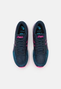 Baskets de sport bleues avec une tige en mesh, des accents roses et une semelle blanche. Elles présentent un design à lacets et une pointe arrondie pour le confort.