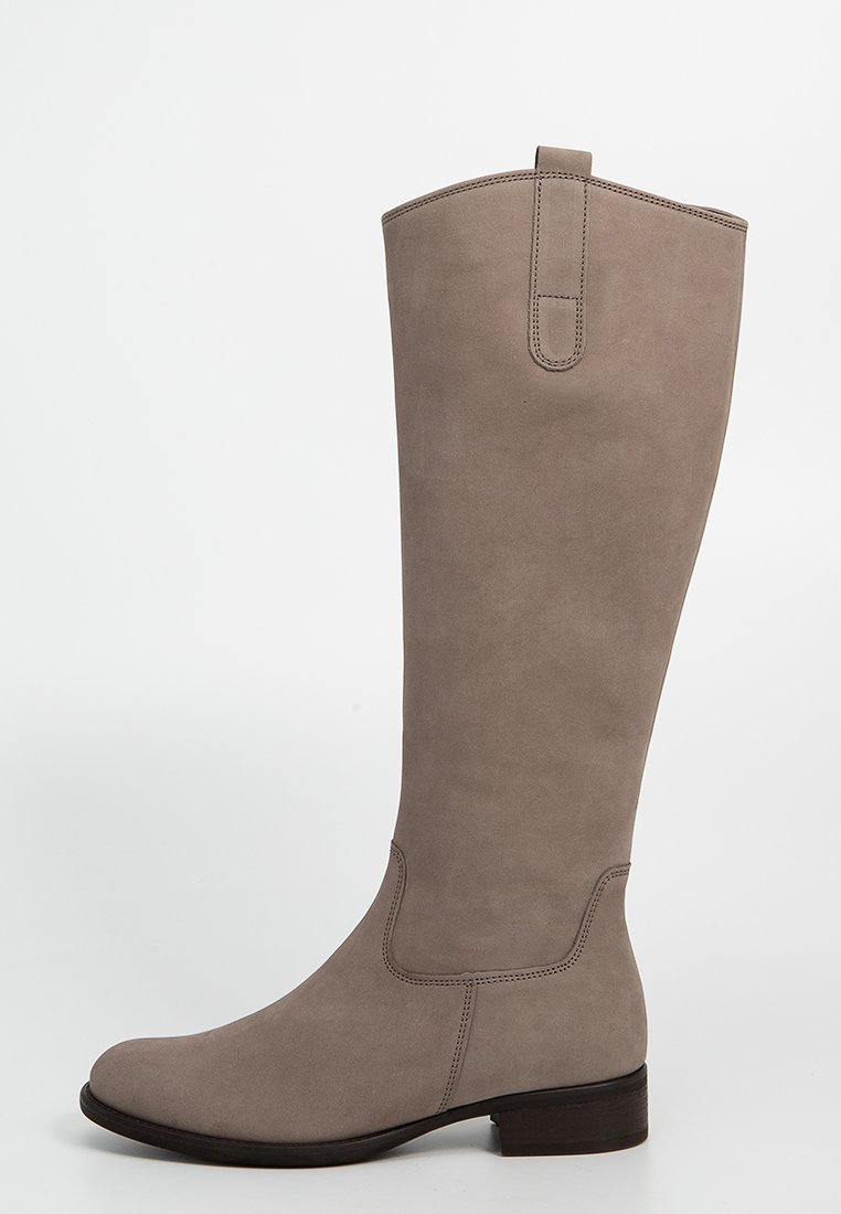 Lange taupe suède laars met een lage hak, ronde neus en een lus aan de bovenkant tegen een effen lichte achtergrond.