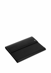 Pochette style portefeuille en cuir noir pliée avec un emblème métallique du logo dans le coin supérieur droit, sur fond blanc.