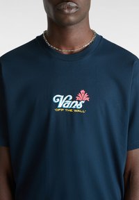 Granatowa bawełniana koszulka z okrągłym dekoltem z wielokolorowym logo "Vans" z kwiatowym detalem oraz hasłem "OFF THE WALL" poniżej w kolorze żółtym.