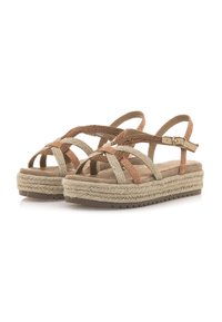 Sandalias tejidas en tonos marrón y beige con tiras cruzadas, que cuentan con una plataforma similar a yute y una correa de tobillo ajustable. Plantilla texturizada.