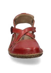 Rode leren schoen met een kruisbandontwerp en verstelbare gespsluiting. Rond toelopende neus en een bruine, gestructureerde zool met zichtbare stikdetails.
