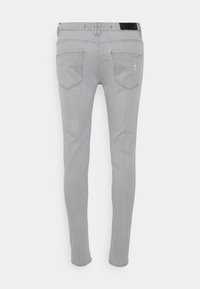 Grå slim jeans med en jämn textur, försedda med bakfickor, subtila sömdetaljer och en svart midjebandsstämpel.