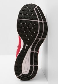 Sole di una scarpa sportiva rossa con una superficie in gomma nera testurizzata, modelli a treccia esagonali e una sezione centrale liscia con un logo.