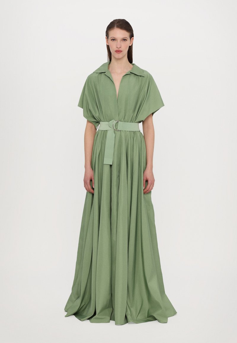 Vestido longo verde com colarinho, mangas curtas e cintura ajustada com um cinto. Textura suave e tecido fluido.