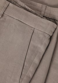 Graue Leinenhosen mit glatter Textur, flachem Bund, seitlichen Taschen und ordentlich genähten Nähten.