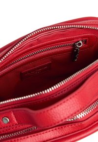 Borsa in pelle rossa con superficie texture. Presenta dettagli in metallo argentato, una chiusura con zip e una tasca interna con etichetta.