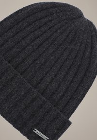 Ciemnoszara dziana czapka typu beanie z prążkowaną fakturą i złożonym mankietem. Posiada małą metkę marki z boku. Tkanina wydaje się miękka i ciepła.